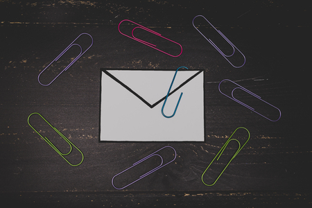 funny metaphor of inbox with email envelop and attachment clip on real-life desk, flatlay shot from topdown perspectiveの写真素材