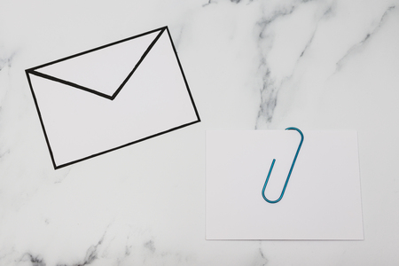 funny metaphor of inbox with email envelop and attachment clip on real-life desk, flatlay shot from topdown perspectiveの写真素材