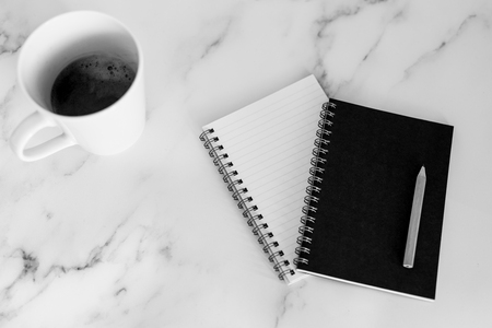 flatlay of mini spiral notebooks with pencil and cup of coffee on marble desk shot from a top down perspectiveの写真素材