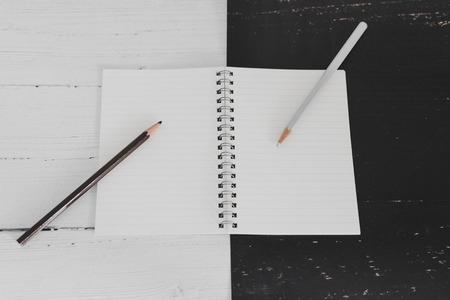 open notepad on black and white background with pencils of the opposite color, contrasty minimalist flatlayの写真素材