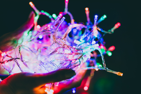 hands holding entangled ball of colorful fairy led lights, concepts of parties and festive seasonの写真素材