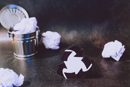 recycle symbol surrounded by scrunched paper balls with garbage bin, concept of reducing damage to the environmentの写真素材