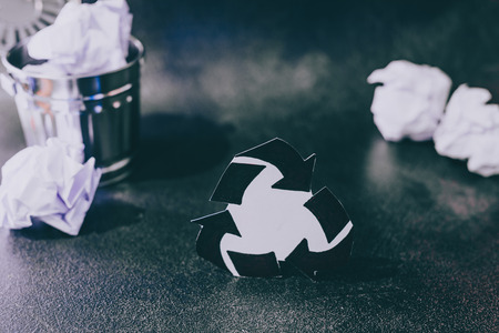 recycle symbol surrounded by scrunched paper balls with garbage bin, concept of reducing damage to the environmentの写真素材