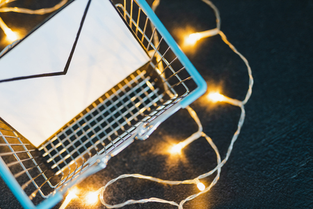 shopping cart with email envelope on concrete desk surrounded by fairy lights, concept of online marketing and customer purchasesの写真素材