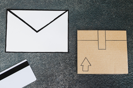 cardboard parcel with email envelope and payment card on concrete desk, concept of shipping and tracking your online deliveriesの写真素材