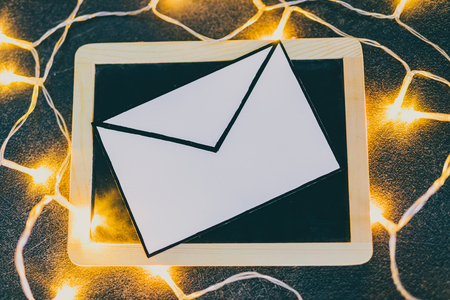 email envelope on blackboard surrounded by fairy lights, metaphor of internet communicationの写真素材