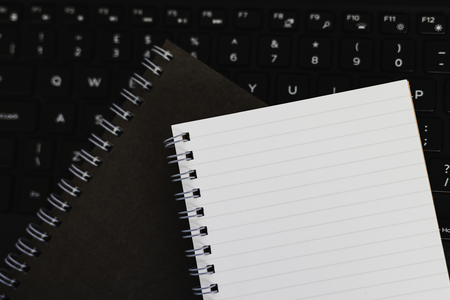 2 paper notepads on top of laptop keyboard, concept of technology vs paper