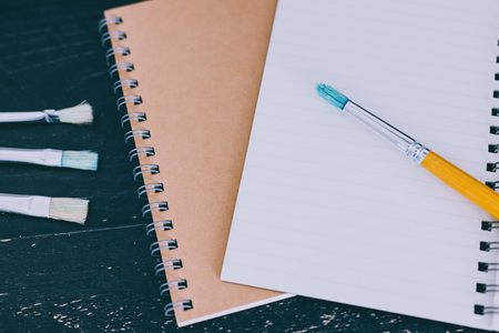 desk with notepads and watercolour brushes with empty pages and copyspace, concept of creativity and inspirationの写真素材