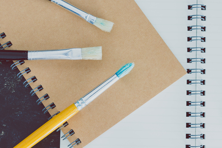desk with notepads and watercolour brushes with empty pages and copyspace, concept of creativity and inspirationの写真素材