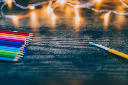 coloured pencils and brush with fairy lights in the background, concept of imagination and creativityの写真素材