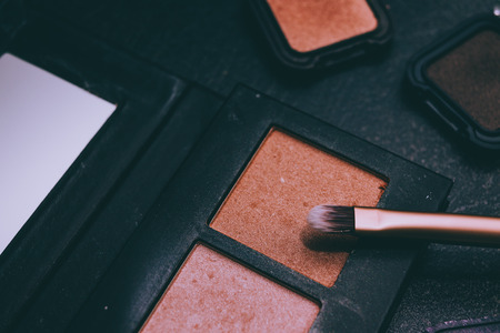 natural toned bronzers eyeshadows and highlighters  with brush on dark background, concept of make-up and cosmetics industry trendsの写真素材