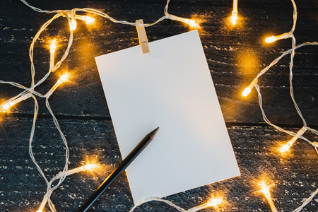 notepad and pencil on wooden desk with copyspace to add you text surrounded by fairy lights, concept of sharing a messageの写真素材