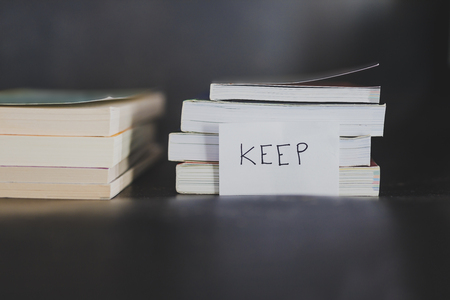 decluttering and tidying up concept: selecting which books to keep and which to discard or donate