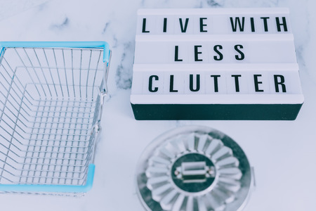 ecology and consumerism concept: live with less clutter message on lightbox with shopping basket and trash binの写真素材