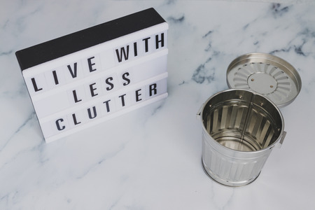 ecology and consumerism concept: live with less clutter message on lightbox with open empty trash...