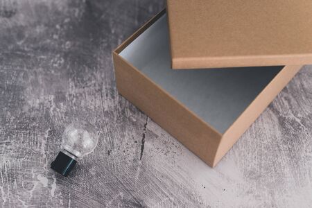think outside the box concept: open empty box with one lightbulb outside of it