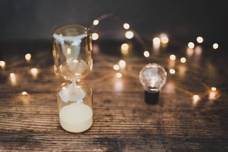 time for new ideas conceptual image with hourglass and lightbulb surrounded by fairy lights bokeh on...