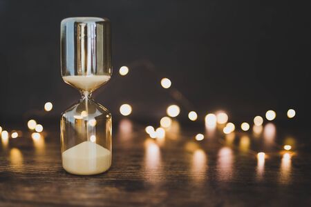 time management conceptual image with hourglass surrounded by fairy lights bokeh on wooden office deskの写真素材