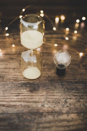 time for new ideas conceptual image with hourglass and lightbulb surrounded by fairy lights bokeh on...
