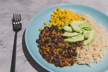 vegan recipes concept: mexican style dish with spicy black bean coconut rice corn and avocado toppingの写真素材