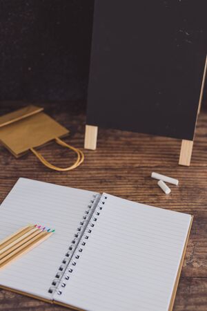 back to school desktop flatlay with coloured pencils blackboard notepad and shopping bag, concept of buying stationery for the new school yearの写真素材