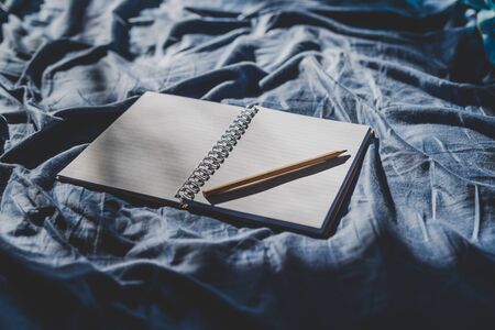 diary notebook on blue bedding; concept of journaling or brainstorming in the morningの写真素材