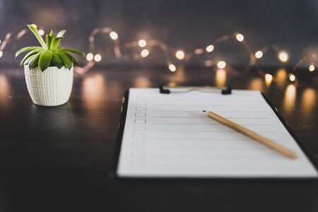 clipboard with blank list with cases to tick off on wooden desk with pencil and succulent, concept of time management and scheduling tasksの写真素材
