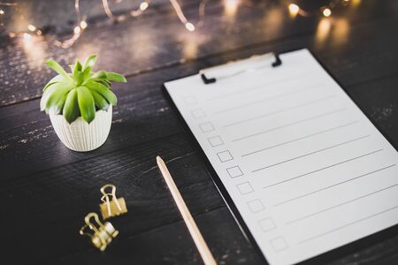 clipboard with blank list with cases to tick off on wooden desk with pencil and succulent, concept...