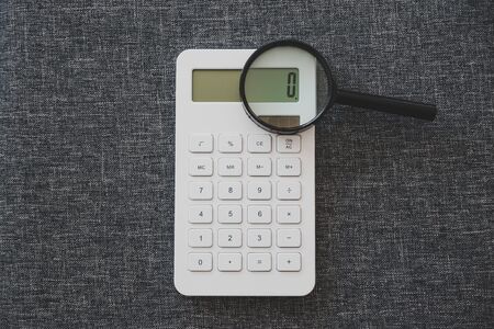 calculator and magnifying glass analyzing it, budget and finance concept