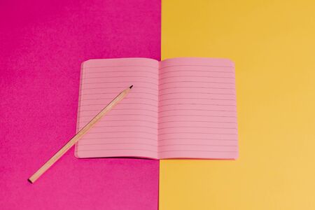 open notebook with blank pink pages with copyspace on contrasting yellow and magenta background