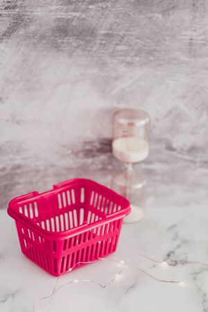 pink shopping basket with hourglass and fairy lights, concept of flash sales and temporary dealsの写真素材