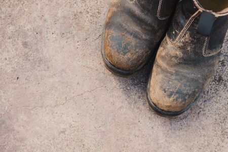 worn out work boots on concrete floor, concept of hard work in the farming or construction industriesの写真素材