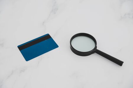 analying your finanaces and budgeting concept, magnifying glass and payment card on desk (minimalistic composition with copyspace)の写真素材