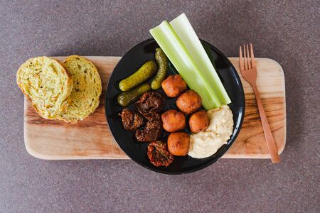 healthy plant-based meal concept, raw veggies falafels and hummus on cutting board with corn bread