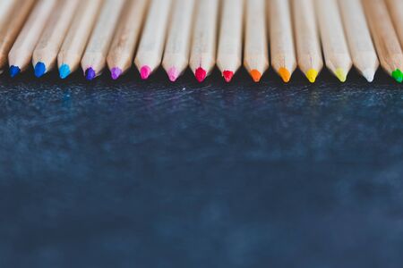 coloured pencils lined up on dark desk in color gradient order with copyspace, close-up versionの写真素材