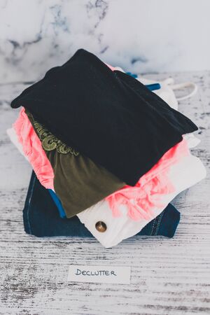 declutter and tidying up concept, fashion clothes folded and stacked into Declutter pile with text on paper label in front of itの写真素材