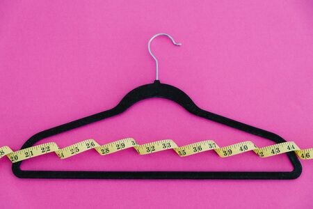 concept of fashion imposing trends of losing weight to fit small sizes, clothes hanger with...