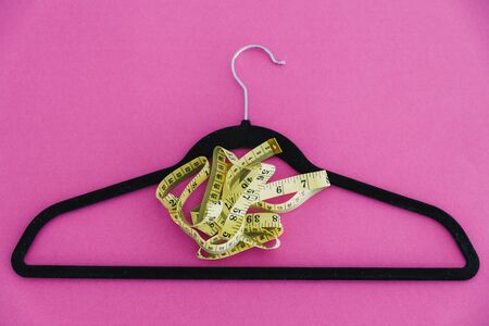 concept of fashion imposing trends of losing weight to fit small sizes, clothes hanger with...