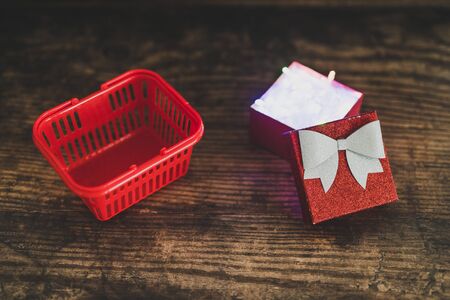 Christmas present box with shining fairy lights inside next to shopping basket, concept of gift...
