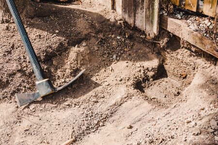 mattock gardening tool to dig the ground and chop weeds left next to fence and hole in the gorundの写真素材