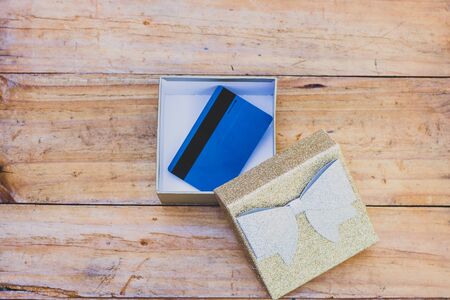 payment card or gift card inside open present box on wooden table, concept of shopping and...