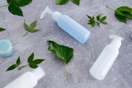 chemical-free natural beauty products concept, group of lotion bottles surrounded by fresh green leavesの写真素材