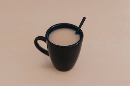 hot bevereages, chai tea with milk in black mug on wooden table of the same color shot from 45 degrees angleの写真素材