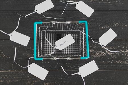 sales strategy and customer purchases, shopping basket surrounded by price tags and one with Sales written on itの写真素材