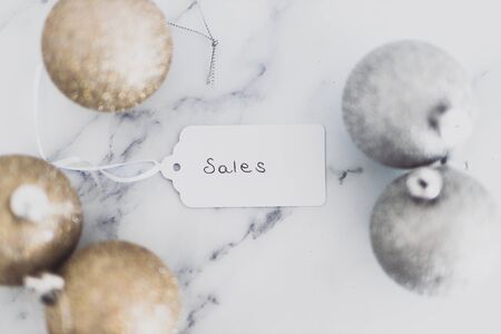 festive season shopping and promotions conceptual still-life, Sales price tag with gold and silver Chirstmas baubles on marble desk shot at shallow depth of fieldの写真素材