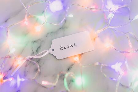festive season shopping and promotions conceptual still-life, Sales price tag surrounded by colorful Christmas lights shot at shallow depth of field black and white versionの写真素材