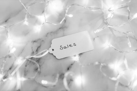 shopping and promotions conceptual still-life, Sales price tag surrounded by fairy lights shot at shallow depth of field black and white versionの写真素材