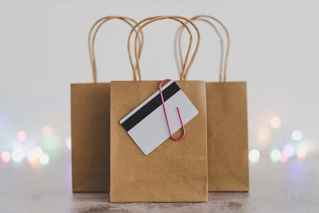 shopping and marketing success conceptual still-life, shopping bag with payment card clipped to it and other bags in the background with fairy lights bokehの写真素材