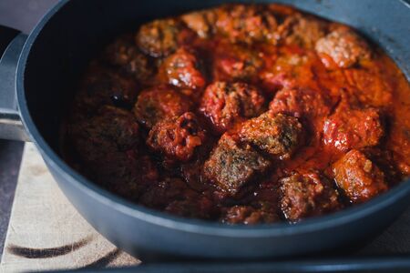 hot vegan meatballs with chilli tomato sauce cooking in a pan, close-up shot