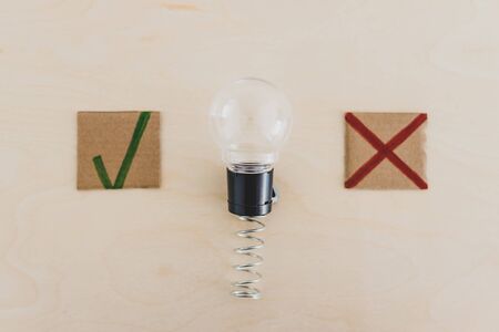 feedback about good and bad ideas conceptual stll-life, lightbulb on spring with green tick and red cross next to itの写真素材